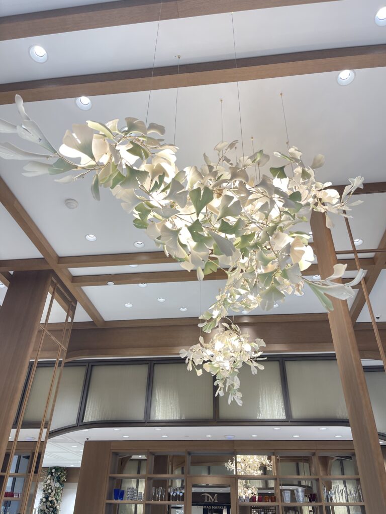 Bespoke porcelain ginkgo-leaf chandelier framed by coffered woodwork at Thomas Markle Jewelers